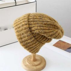 a knitted hat sitting on top of a wooden stand next to a white box