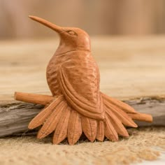 a wooden bird sitting on top of a piece of wood