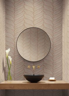 a bathroom sink sitting under a mirror on top of a wooden counter next to a vase with flowers