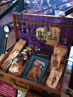 an open suitcase filled with lots of jewelry and necklaces on display in a store