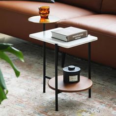 a coffee table with a book and candle on it in front of a brown couch