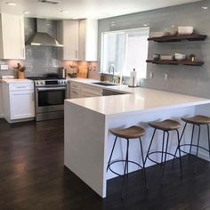 a kitchen with three stools next to an island