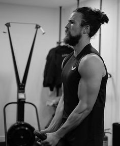 a man with long hair and beard standing in front of a gym machine