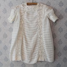 "Vintage late 1910s to early 1920s young girl's sheer cotton ivory pintucked and Irish lace inset dress. The dress is loose fitting and features a high squared neck with heavy Irish lace insets around the collar, vertically down the front and back and on the cuffs of the sleeves. The entire dress also feature triple rows of delicate pin tucks. The front of the dress buttons up the side and up the collar with 5 hidden small round mother of pearl buttons and small threaded loops. This dress along Cream Victorian Dress With Lace Trim For Daywear, Vintage Dresses For First Communion In Spring, White Vintage Dress With Lace Patchwork For Daywear, Vintage Cream Dress For First Communion, Fitted Vintage Victorian Dress For Baptism, Irish Lace, Lace Inset, Silk Slip, Mother Of Pearl Buttons