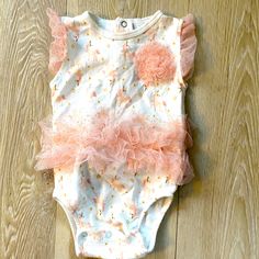 Nwot Sz 6-9 Mos Tahari Bodysuit. It Is Cream Colored With Pink Tulle Accents. The Pattern Is Unicorns And Stars. It Has A Decorative Flower, A Tutu Around The Waist, And Tulle Ruffles Around The Arm Openings. There Are Three Snaps On The Back Of The Neck And Three Snaps On The Bottom For Easy Changes. Pink Bubble Romper For Playwear In Spring, Pink Bubble Romper For Spring Playwear, Pink Fitted Bubble Romper For Playtime, Fitted Pink Bubble Romper For Playtime, Pink Fitted Bubble Romper For Spring, Spring Fitted Pink Bubble Romper, Fitted Pink Bubble Romper For Spring, Pink Sleeveless Onesie, Pink Playful Bubble Romper For Playwear