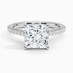 a princess cut diamond ring with pave set diamonds on the shoulders and sidestones