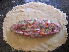 an uncooked pizza dough with meat and veggies on it