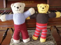 two knitted teddy bears standing next to a piano