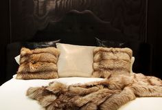 a bed with two pillows on top of it and some furs around the edges