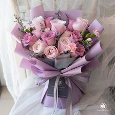 a bouquet of pink roses wrapped in purple ribbon