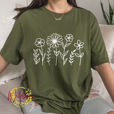 Wildflower Shirt, Wild Flower shirt, Wild flowers T-shirt, Floral Shirt, Flower T shirt, Botanical gift for her, birthday gift for her, flower graphic tee shirt for women, mothers day outfit, gift for mom, Boho Wildflower nature shirt, botanical shirt You select the size and color of your shirt.  There is a photo showing you the shirt colors. *Note the difference between solid colors and heather colors. The shirt colors available for the listing you are looking at will be in the drop-down menu. The shirts used are adult Bella+Canvas 3001 Unisex shirts. They are of a soft and lightweight fabric. The shirts are unisex, they are not a women's fitted style. Please refer to the sizing info/measurements so that you can order the correct size. We do not accept returns or exchanges. Please note th Trendy Green Floral Print Shirt, Trendy Short Sleeve Shirt With Plant Print, Cotton Floral Print Short Sleeve T-shirt, Green Graphic Tee With Plant Print, Green Graphic Tee With Plants Print, Green Short Sleeve Shirt With Plant Print, Green Cotton T-shirt With Plant Print, Floral Print Short Sleeve Cotton T-shirt, Casual Green Tops With Plant Print