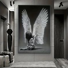 a black and white photo of a woman with angel wings on her body sitting in front of a mirror