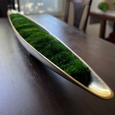 a wooden table topped with a plate covered in green moss