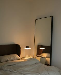 a bedroom with a bed, mirror and lamp on the nightstands in front of it