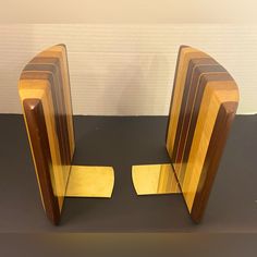 two wooden bookends sitting next to each other on a black counter top in front of a white wall