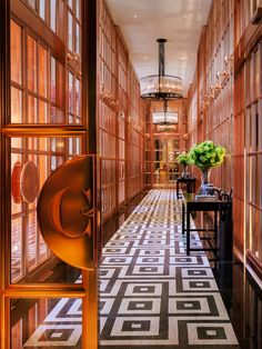 the hallway is lined with wooden paneled walls and flooring, along with vases filled with flowers