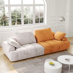 an orange and white couch sitting on top of a wooden floor next to a table