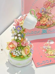 a vase filled with lots of flowers next to a pink box and greetings card