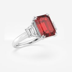 Get lost in the mesmerizing facets of this emerald cut three stone ring, featuring a striking red ruby that's sure to turn heads. The emerald cut's clean lines and geometric precision bring an enchanting shimmer to the vibrant gem, while its elongated shape creates an elegant look on the finger. Accented by diamond side stones, this emerald cut ruby ring embodies old world sophistication. Formal Red Ruby Ring With Three Stones, Formal Ruby Three Stone Ring, Red Baguette Cut Lab-created Ruby Ring, Formal Red Three Stone Ruby Ring, Red Baguette Cut Diamond Ring, Luxury Red Three Stone Jewelry, Luxury Red Three-stone Jewelry, Gia Certified Baguette Cut Ruby Ring, Gia Certified Emerald Cut Ruby Ring