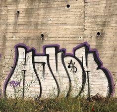 graffiti on the side of a building with purple and black letters in front of it