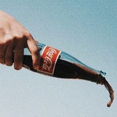 a person holding onto a bottle in the air with their hand on top of it