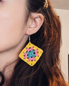 a close up of a person wearing earrings with crocheted designs on them,