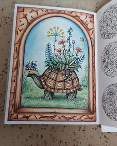 an open book with pictures of flowers and a tortoise on the cover, sitting on a table