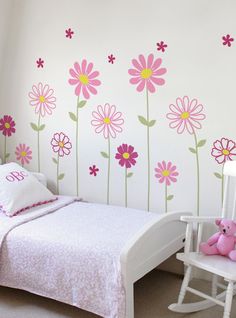 a child's bedroom with flowers painted on the wall and rocking chair next to it