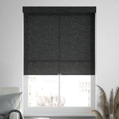 a living room with a couch, chair and window covered in black roman blind shades