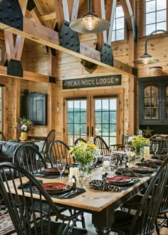 a dining room table with black chairs and wooden walls