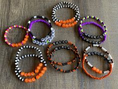 six bracelets with words on them sitting on top of a wooden table next to each other