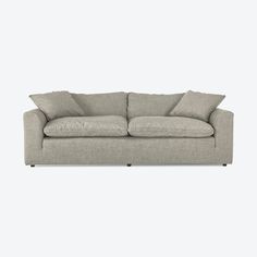 a light gray couch with pillows on the arm and back cushions, sitting against a white wall