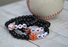 These bracelets are a perfect way to cheer on the kiddos when you are at their sports games  Each bracelet has letter beads with the word 'mom'  and each with an additional bead representing the  ball of each sport. They are simple, unique and super fun even to layer with other bracelets.  One size fits most.  One of each available: Football Baseball  Basketball Team Spirit Bracelets With Letter Beads, Sporty Beaded Bracelets With Letter Beads For Sports Events, Personalized Black Sporty Bracelets, Sporty Letter Beads Wristband For Sports Events, Sporty Bracelets With Round Beads For Sports Events, Sporty Personalized Black Bracelets, Sporty Personalized Black Bracelet, Sporty Wristband With Letter Beads For Sports Events, Team Spirit Letter Beads Bracelets For Gift