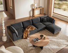 a living room with a large sectional couch and coffee table in front of the window