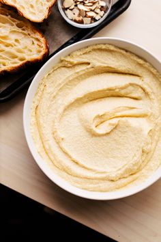 a bowl of hummus next to some sliced bread