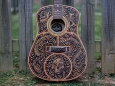 an intricately carved guitar sits in front of a wooden fence