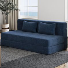 a blue couch sitting on top of a rug next to a window