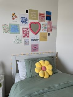 a bed with a green comforter and a yellow flower on the pillow in front of it