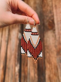 a hand holding a beaded pair of earrings