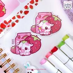 two stickers on top of a table with strawberries and other items in the background