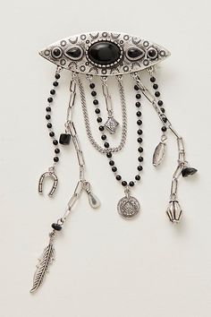 a black and silver brooch with beads on it's side, hanging from a chain