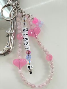 a pink beaded keychain with charms attached to it and a mirror in the background