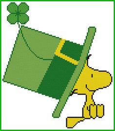 a cross stitch pattern of a dog with a green hat and shamrock leaf on its head