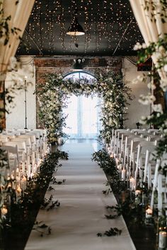 the aisle is lined with candles and greenery for an outdoor wedding ceremony at night