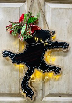 a black dog is hanging on the front door with christmas lights and decorations around it