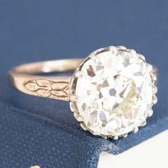 A gorgeous old mine cut diamond ring in the 4ct range sitting in her OG two-tone mounting with the sweetest details! She's a 4.32ct GIA N color and SI1 clarity with a much brighter, cleaner face-up than the grading expresses. The stone sits in a buttercup style setting with charming swoopy details and an engraved floral motif on each of the shoulders. We absolutely love this ring - perfect for those maximizing size over specs. 18kt rose gold & platinum Size 6.5 & fully resizable Diamond measures Heirloom White Diamond Ring With Rose Cut Diamonds, Antique White Jewelry With Prong Setting, Heirloom White Rose Cut Diamond Ring, Victorian White Brilliant Cut Diamond Ring, White Victorian Style Brilliant Cut Diamond Ring, Antique White Jewelry With Center Stone, Victorian White Diamond Ring With Prong Setting, Antique White Ring With Center Stone, White Diamond Ring With Rose Cut