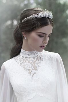 a woman wearing a white dress and a tiara in the middle of a forest