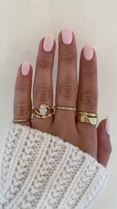 a woman's hand with three gold rings on it and two white sweaters