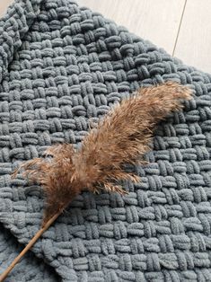 a brown feather resting on top of a blue blanket next to a wooden flooring board