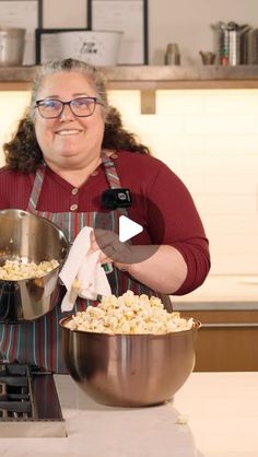 a woman in an apron holding two bowls of popcorn